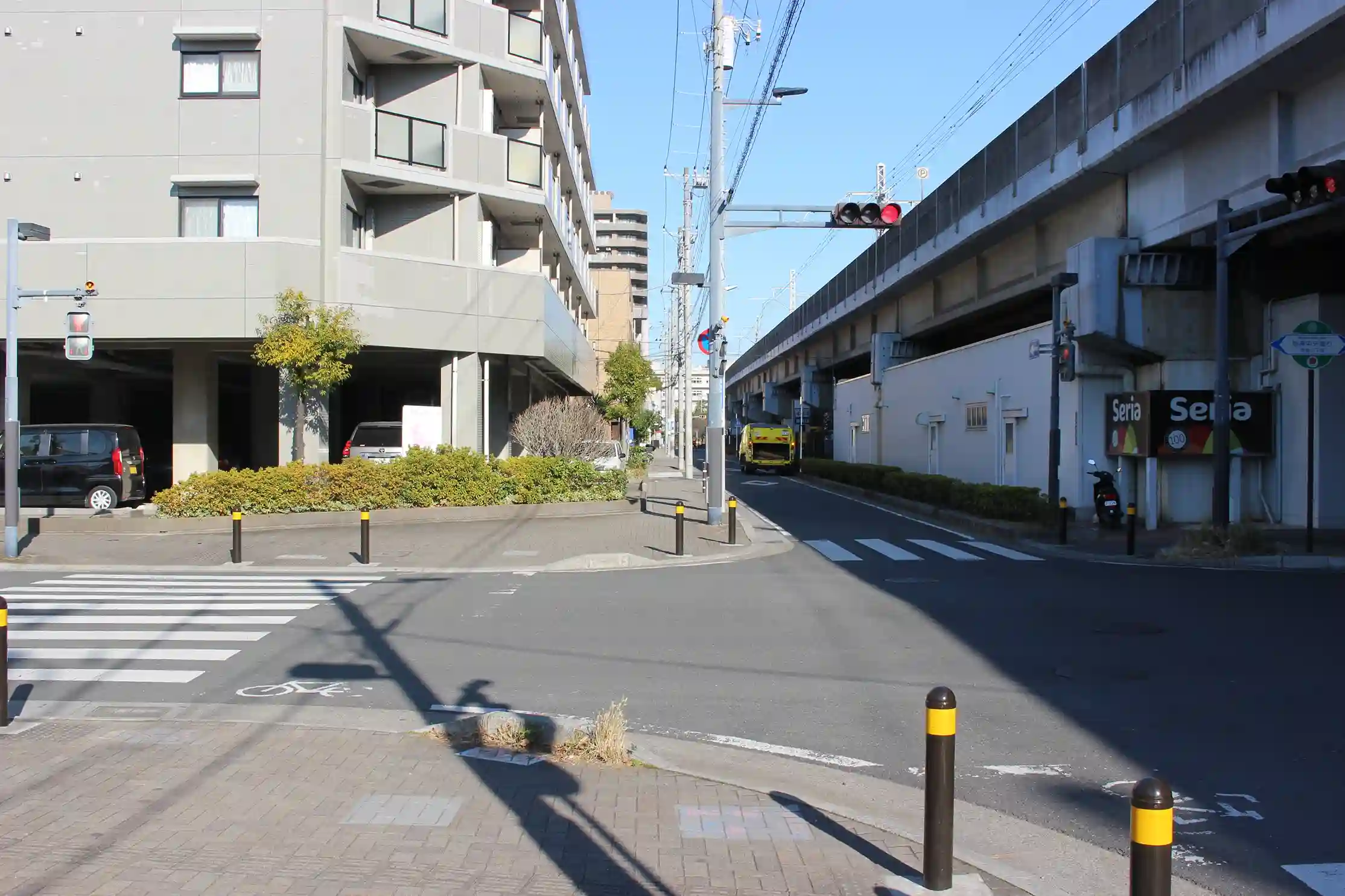 高架下にある100円ショップのSeria（セリア）が見える交差点。ここも高架線に沿って真っすぐ進みます。