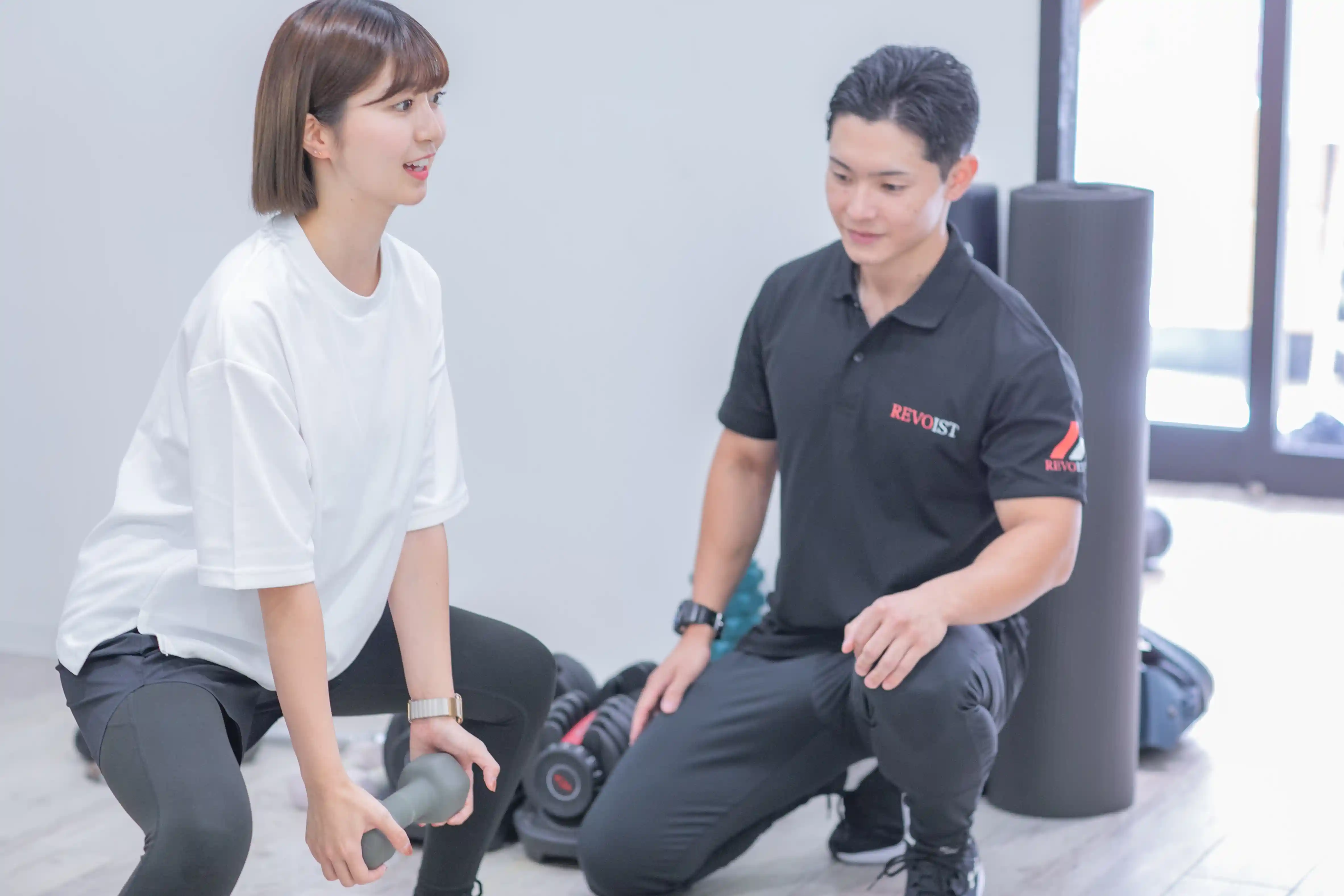 浦安のパーソナルジム「REVOIST」の体験トレーニング風景。現在のお客様の体力に合わせた適切な負荷でのスクワットを、トレーナーのサポートのもとで体感していただきます。