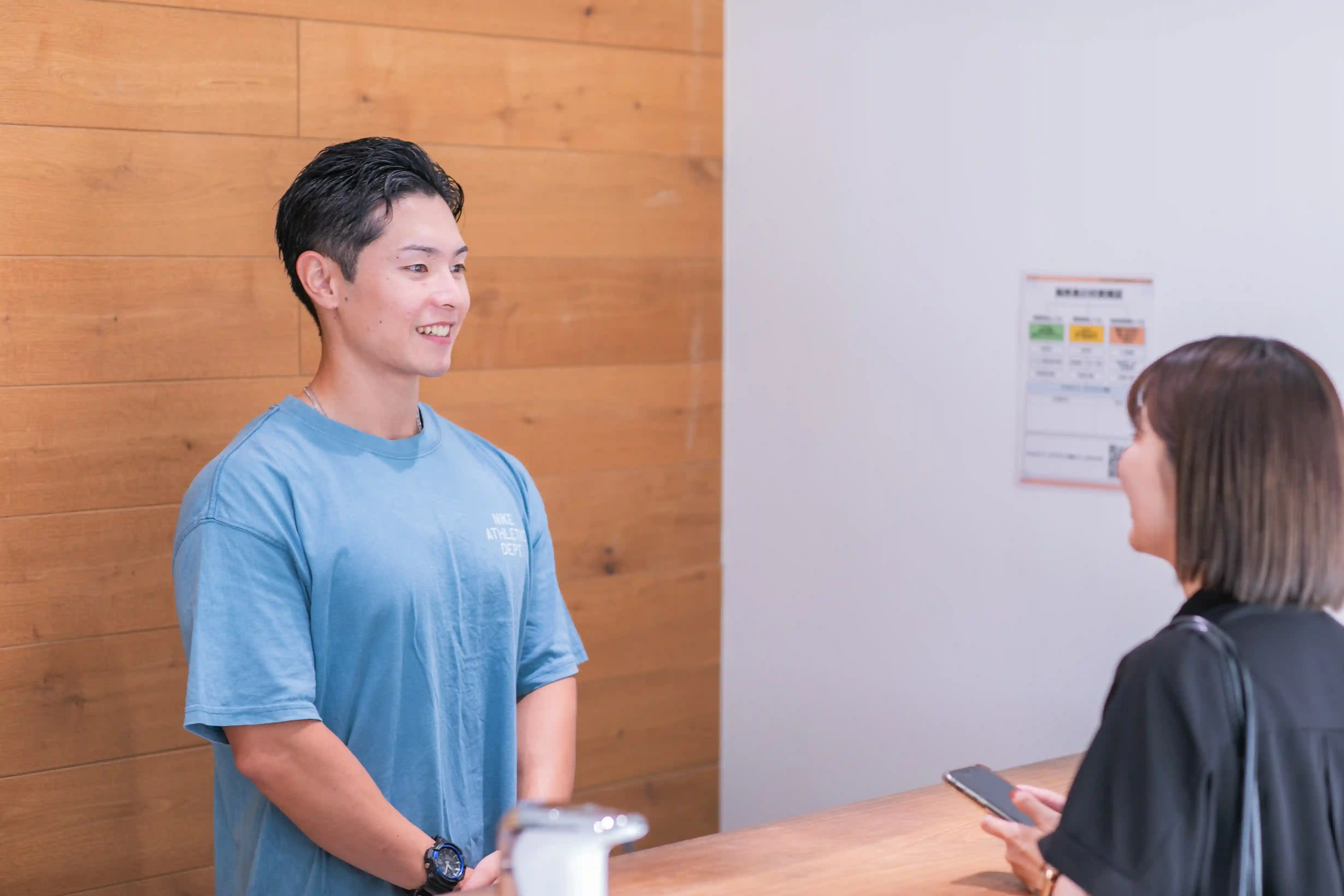 浦安のパーソナルジム「REVOIST」の受付風景。ご来館されたお客様を、トレーナーが笑顔で温かくお迎えします。初めての方も安心してお越しください。